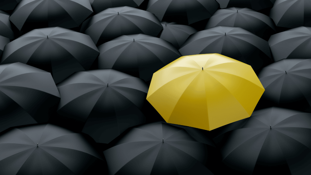 Plusieurs parapluies noirs avec un seul jaune au milieu