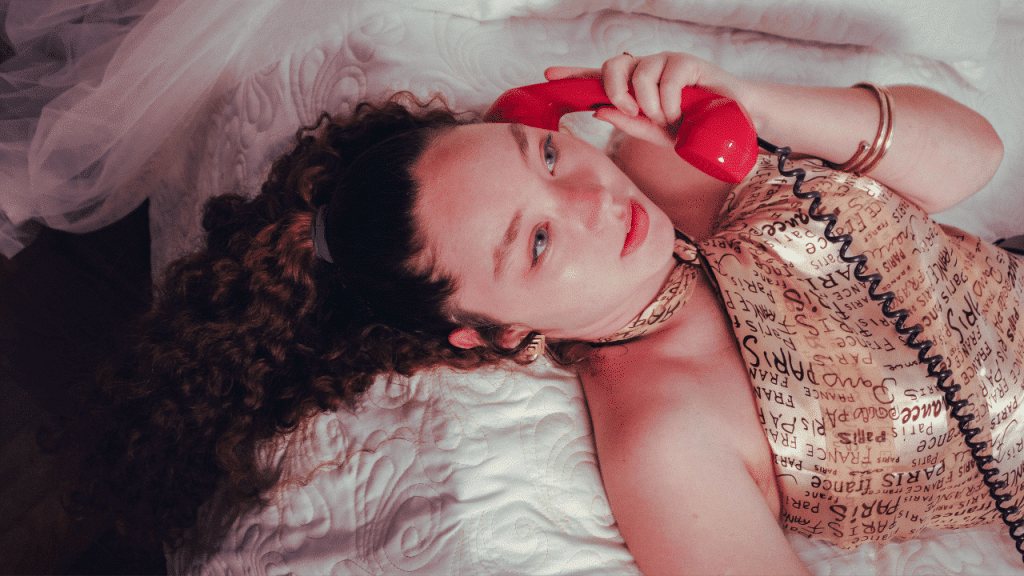 Une jeune femme avec un téléphone combiné rouge à l'oreille