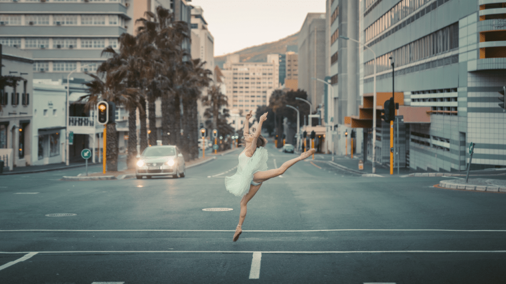 Une danseuse en tutu faisant une figure de danse classique au milieu de la route