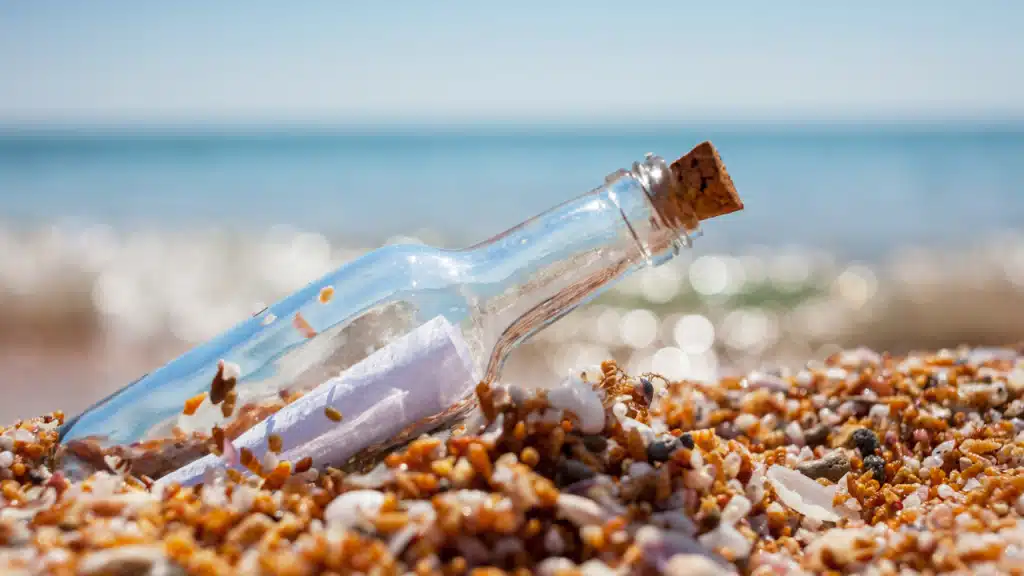 Une bouteille en verre échouée sur le sable avec un message dedans