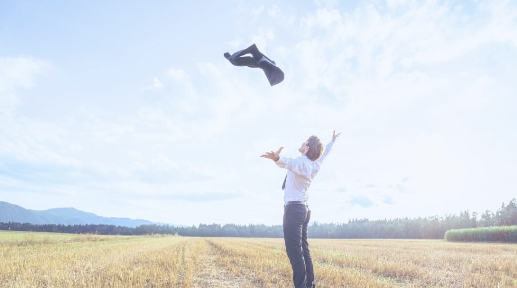 homme dans un champ jetant la veste de son costume dans les airs