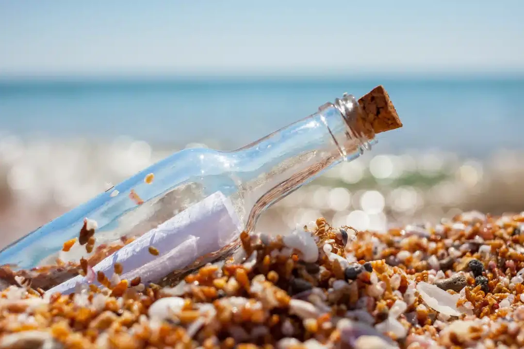 Une bouteille en verre échouée sur le sable avec un message dedans