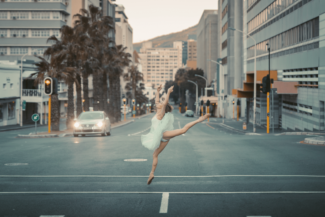Une danseuse en tutu faisant une figure de danse classique au milieu de la route
