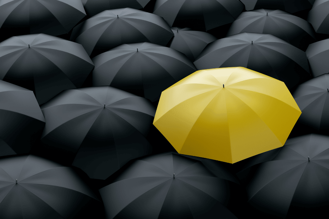 Plusieurs parapluies noirs avec un seul jaune au milieu