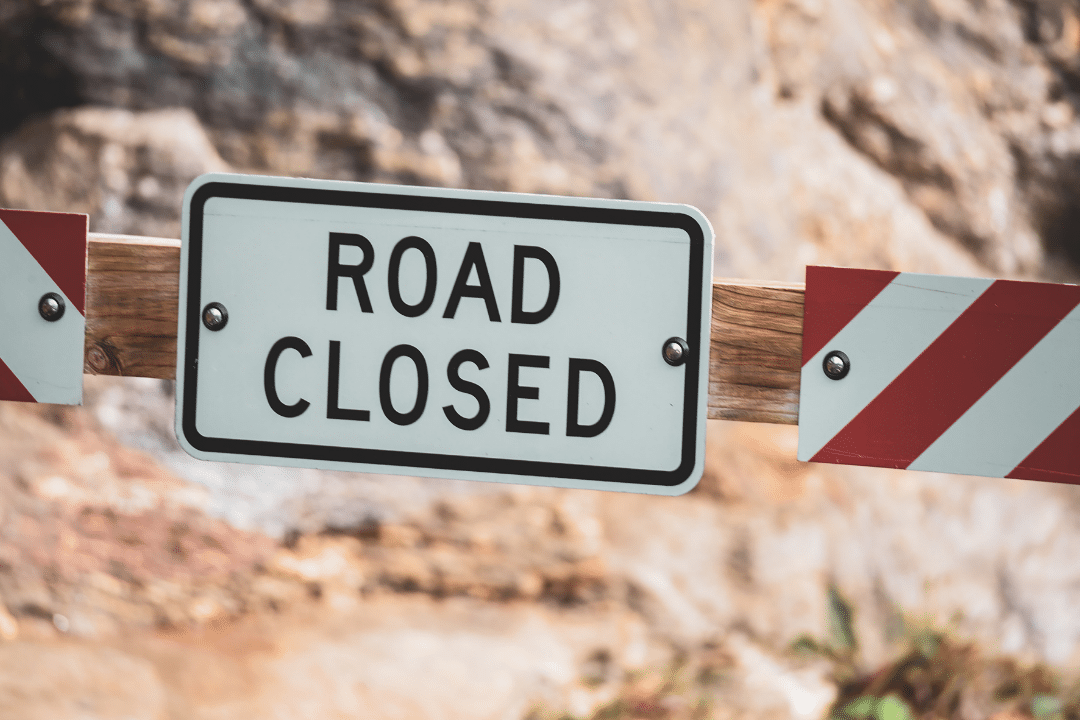 Une barrière avec un panneau ROAD CLOSED (route fermée)