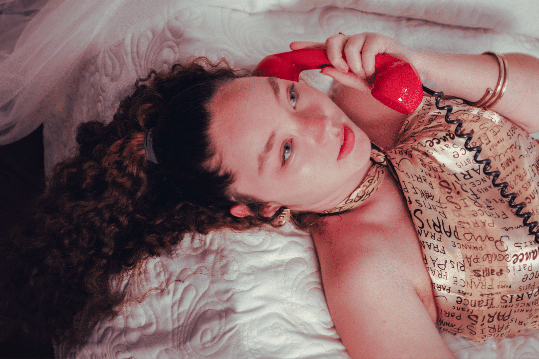 Une jeune femme avec un téléphone combiné rouge à l'oreille